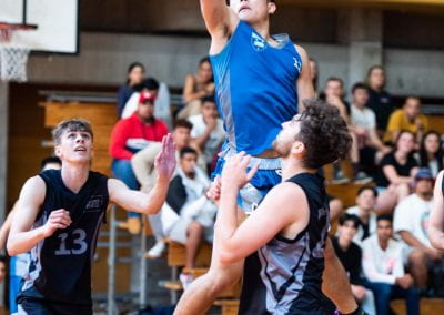 University of Auckland student shooting a hoop in basketball against two AUT defenders