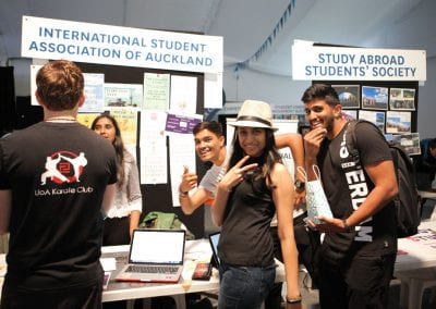 Students smiling at camera in front of International Student Association of Auckland stall