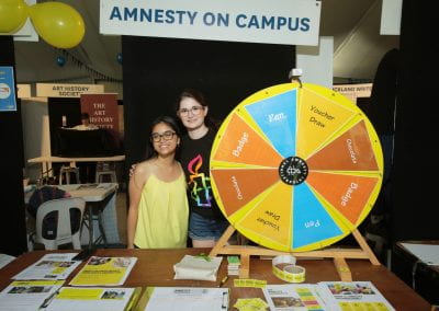 Two students at Amnesty on Campus stall with prize wheel