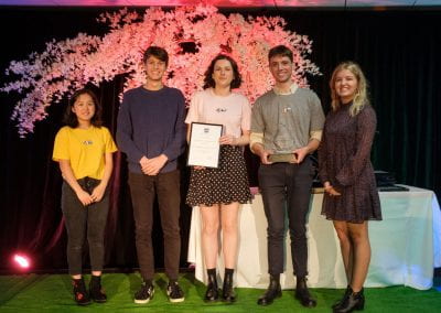 Five students on stage holding an Academic Club of the Year certificate and trophy
