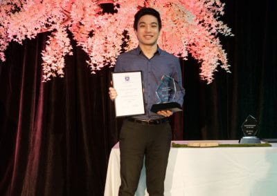 Student on stage holding a Secretary of the Year certificate and trophy